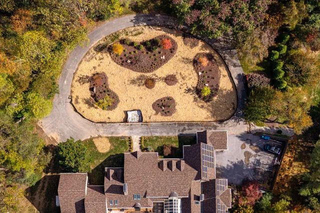 Aerial drone view of a freshly graded circular island planting bed with new shrubs and plantings installed around a residential estate