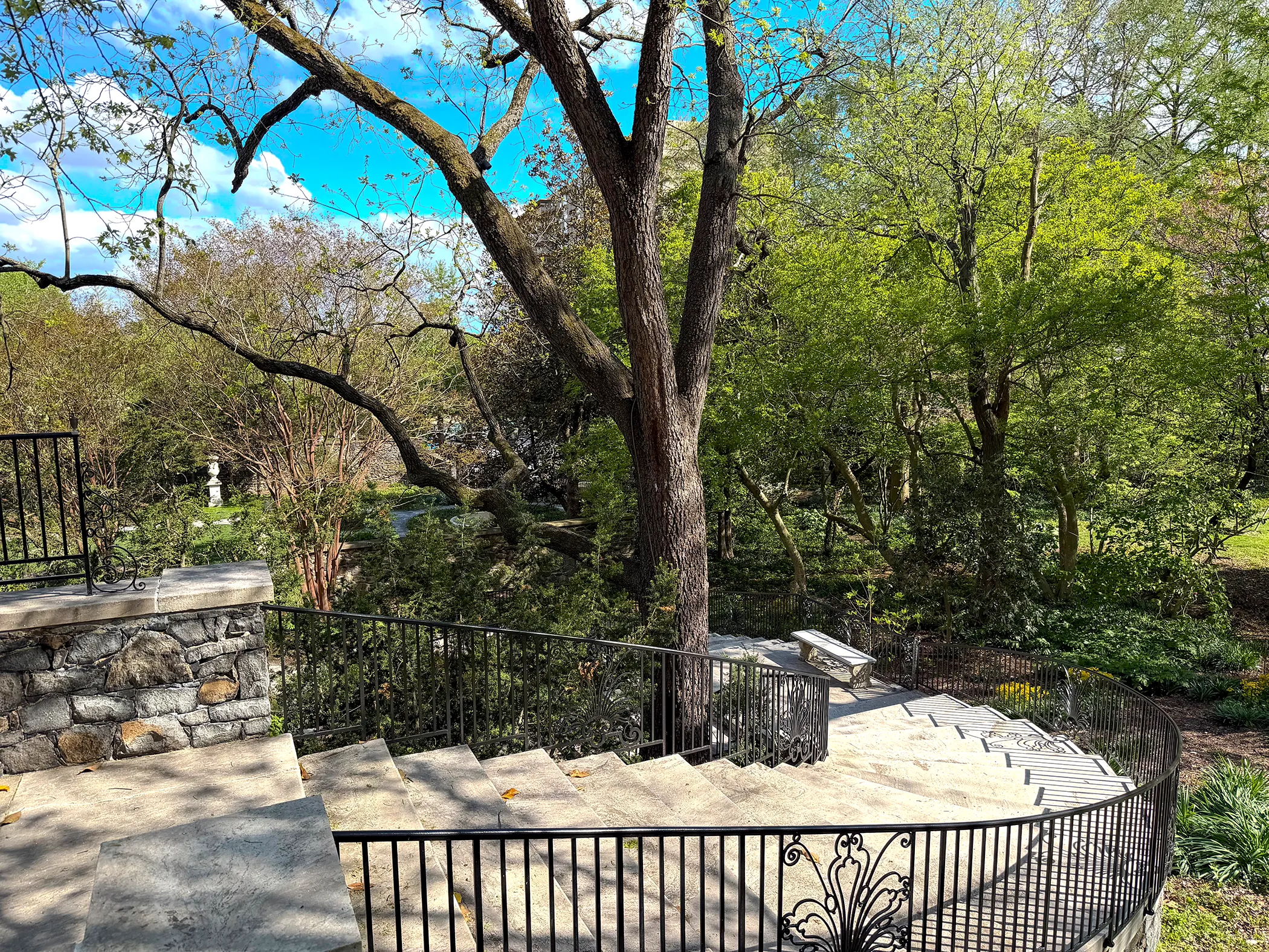 Restored marble staircase at Gibraltar Estate with ornate wrought iron railings, stone retaining wall, and terraced gardens below, spring 2025