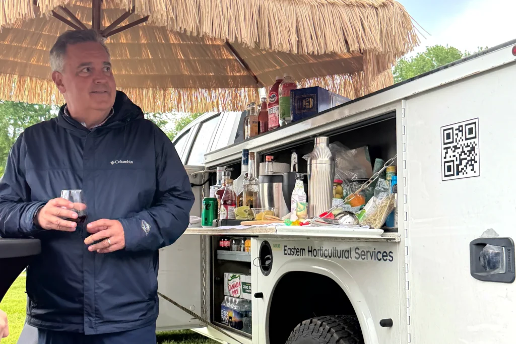 John Winterbottom of Eastern Horticultural Services standing at the EHS mobile bar setup at the 2026 Willowdale Steeplechase in Kennett Square PA