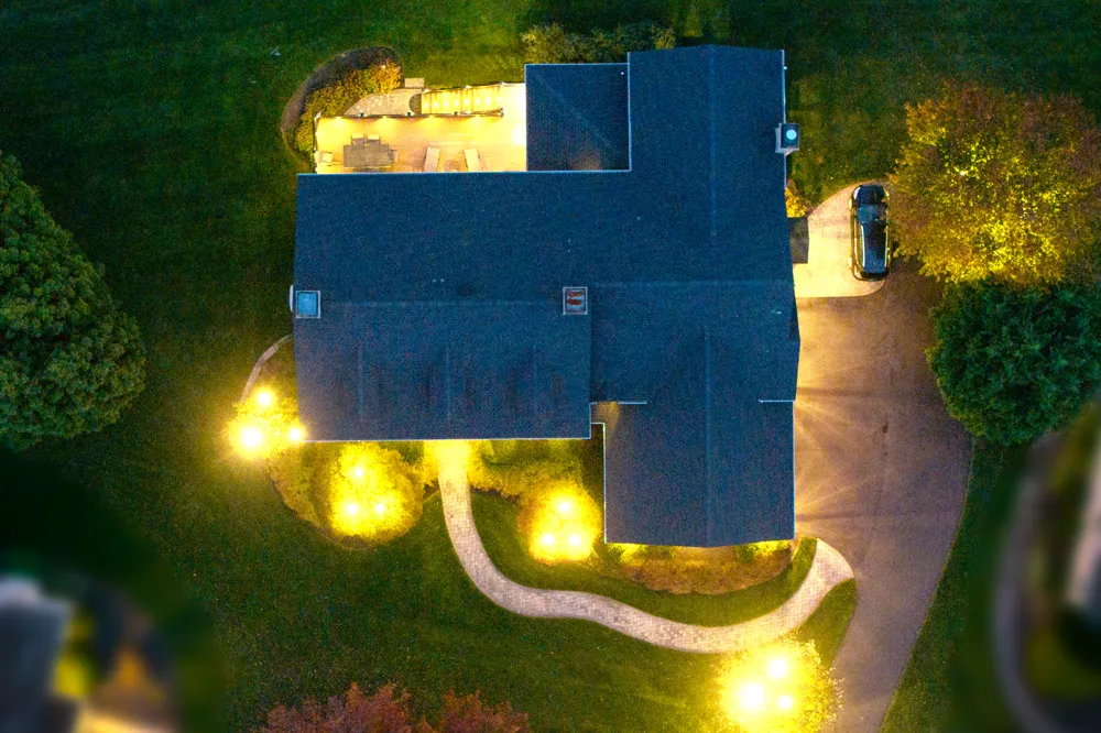 Overhead aerial view of residential property at night showing landscape lighting layout with specimen tree uplights, paver walk, and rear patio illumination — lighting design by Eastern Horticultural Services