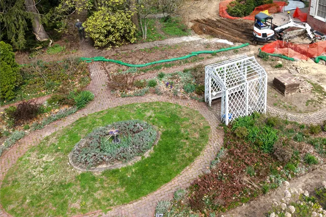 Aerial view of a formal walled garden restoration in progress with circular brick paths, cleared planting beds, and lattice garden arbor — restoration planting by Eastern Horticultural Services