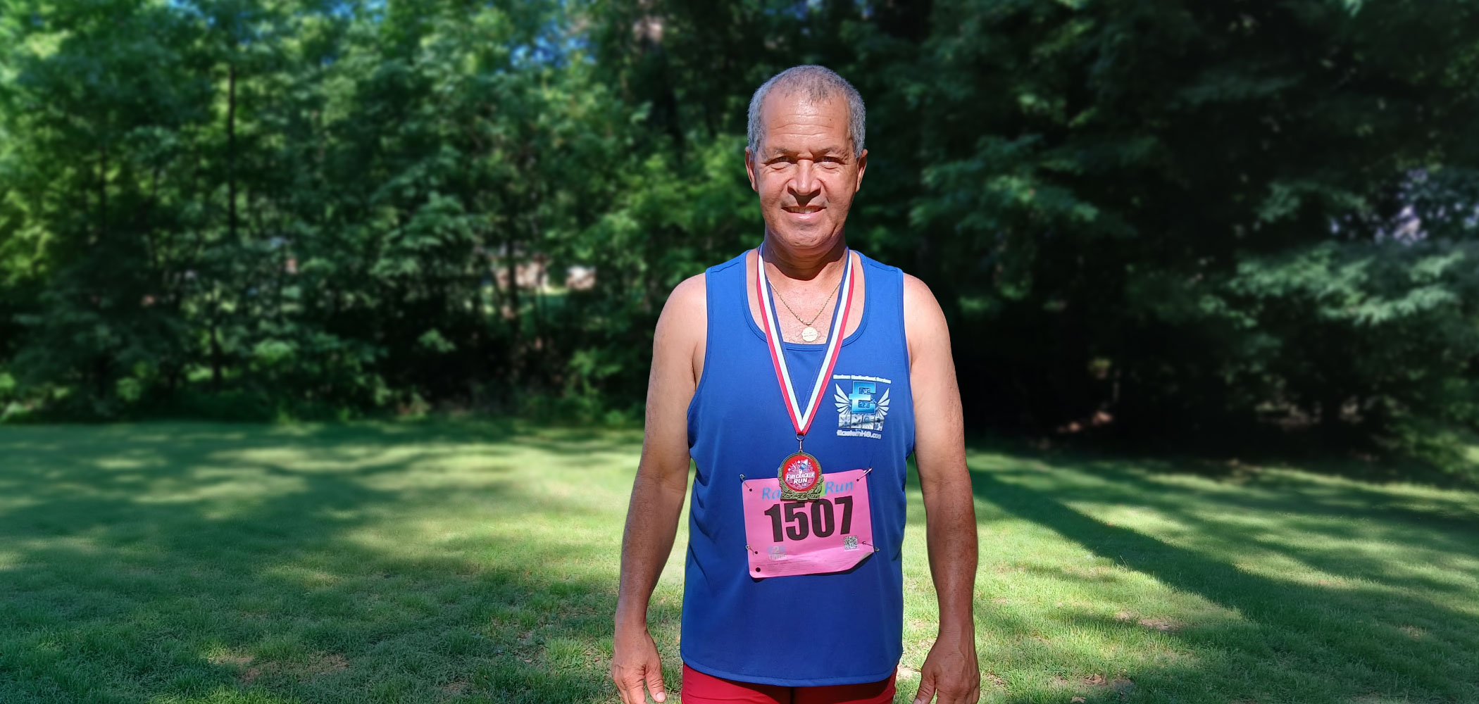 Gerardo Rivas wearing Eastern Horticultural Services gear and a finisher medal after the Rockford Park Firecracker 5K, July 4, 2026.