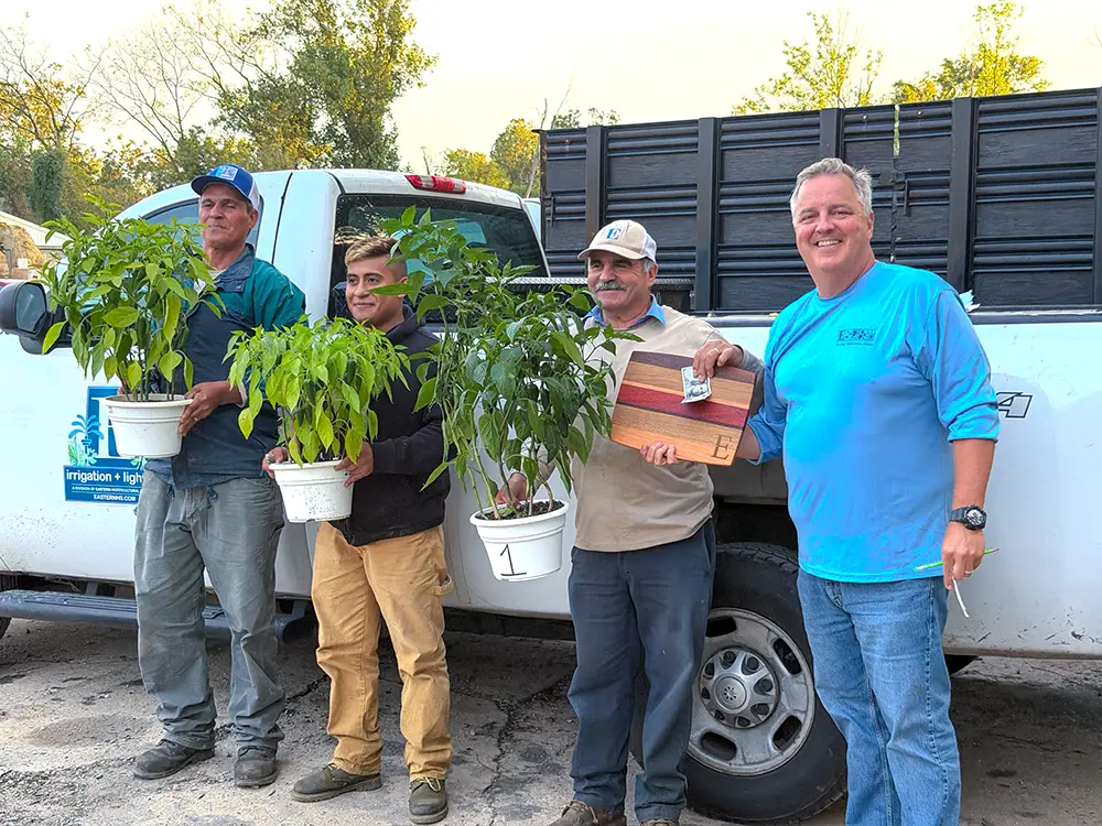 John Winterbottom presenting a striped hardwood cutting board and cash prize to a winning grower in front of an EHS truck