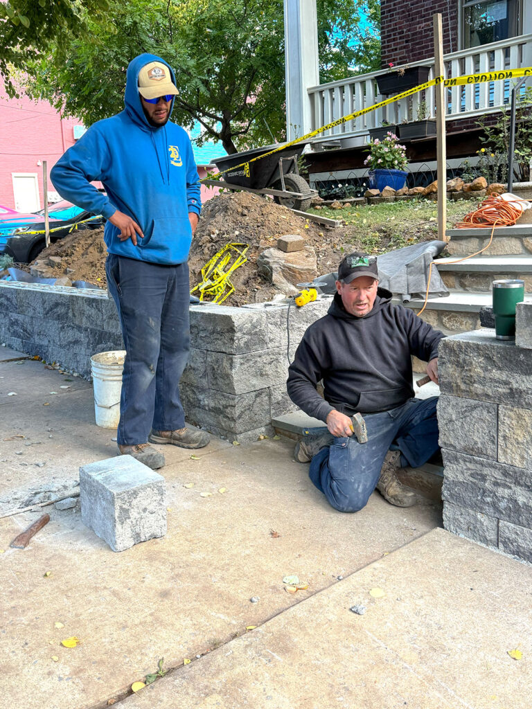 EHS crew member trimming and setting Diamond Pro block beside the front steps during installation